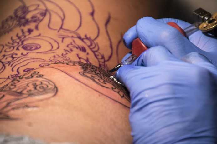 Tattoo artist creating a dragon tattoo